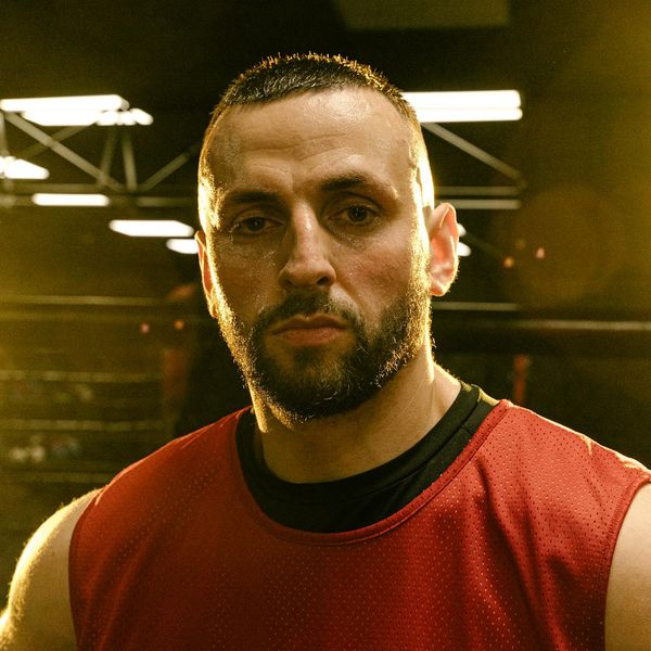 A fit man looking confidently forward after a workout session with soft lavender light behind.